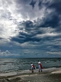 People at beach against sky