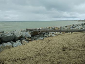 Rocks on beach by sea against sky