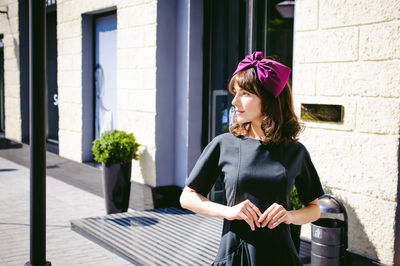 Young woman smiling while standing against wall