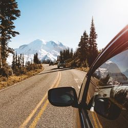 Empty country road along trees and against sky
