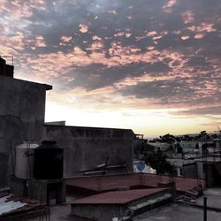 Houses in city against sky during sunset