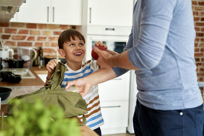 Midsection of father giving apple to son