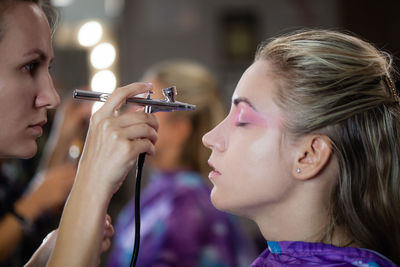 Make-up artist spraying make up on woman at studio