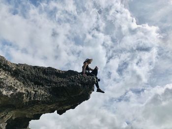 Low angle view of people on rock against sky