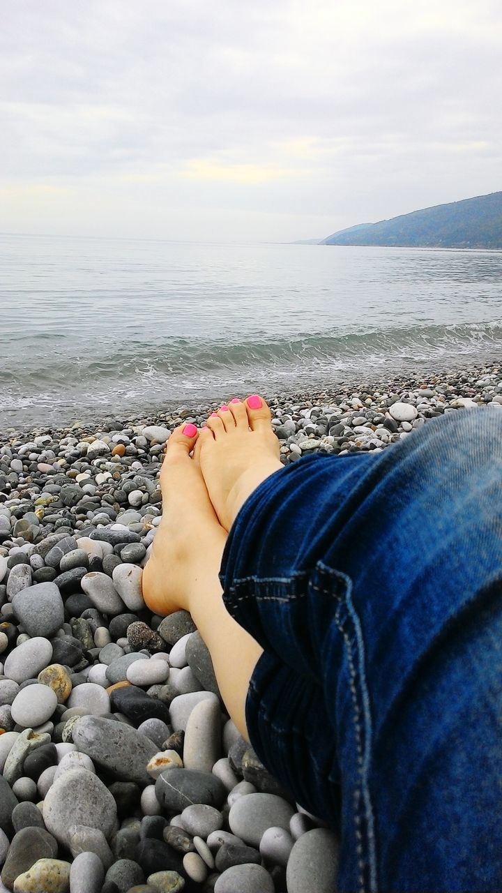 sea, lifestyles, water, low section, person, personal perspective, beach, leisure activity, sky, relaxation, shore, sitting, men, vacations, horizon over water, tranquility