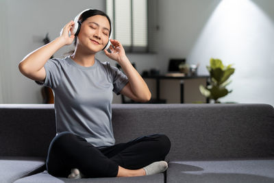 Young woman using mobile phone while sitting at home