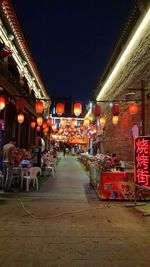 Illuminated street amidst buildings at night