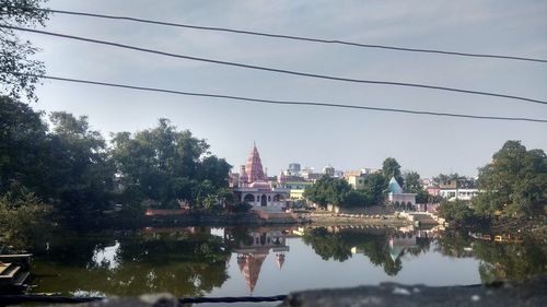 Reflection of buildings and trees on river against sky