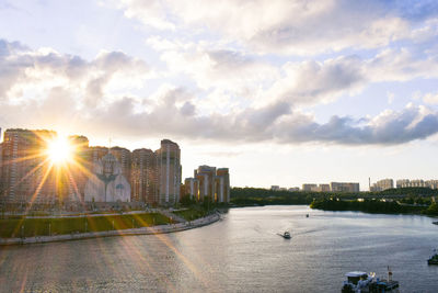 River by buildings against sky during sunset