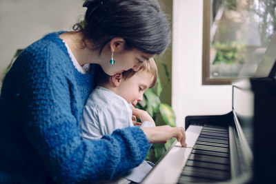 Mother and son playing piano at home