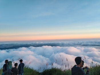 Rear view of people on landscape against sky during sunset