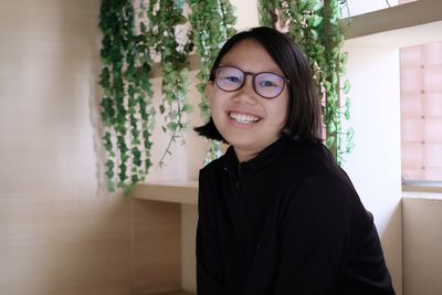 Portrait of girl wearing eyeglasses sitting at home