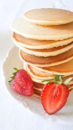 Close-up of pancakes with strawberry slices in plate