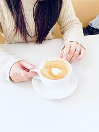 Midsection of woman holding coffee cup on table