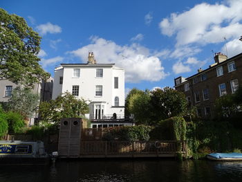 Buildings by river against sky in city