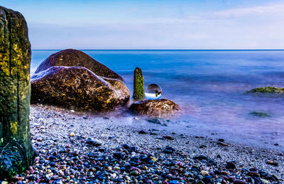 Scenic view of rocks on beach against sky