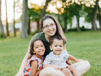 Young millennial mother and diverse mixed race children at park having fun bonding as family 