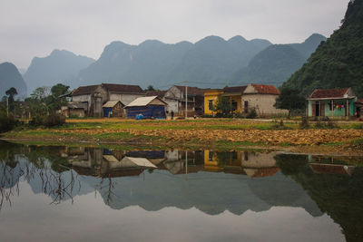 Houses by lake and mountains against sky