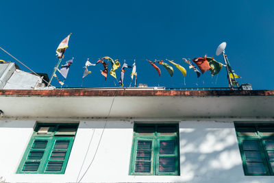 Low angle view of flags on building against blue sky