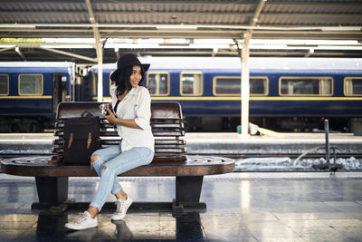 Portrait of woman sitting on railroad station platform