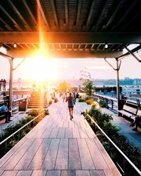 Rear view of people walking on water at sunset