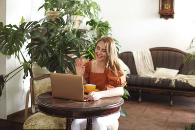 Woman using phone while sitting on table at home