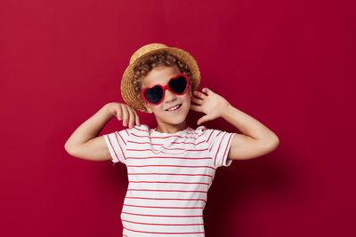 Portrait of smiling boy wearing hat against red background