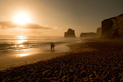 Man and woman standing on beach during sunset