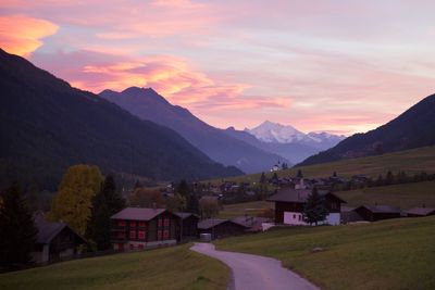 Houses by mountains against sky during sunset