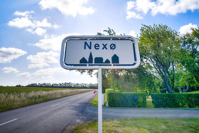 Information sign by road against sky