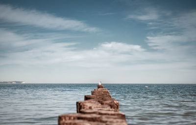 Wooden posts in sea against sky