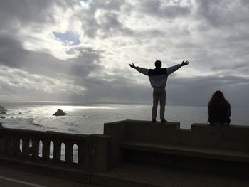 Man standing on beach against cloudy sky