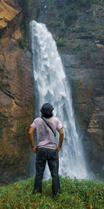 Rear view of man standing against waterfall