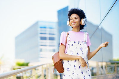 Portrait of young woman standing against building