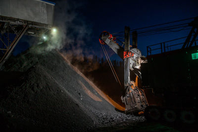 Illuminated working on road by factory at night