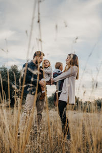 Delighted couple playing with little children while having fun together in countryside at weekend