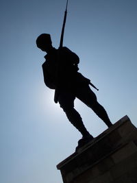 Low angle view of silhouette statue against clear blue sky