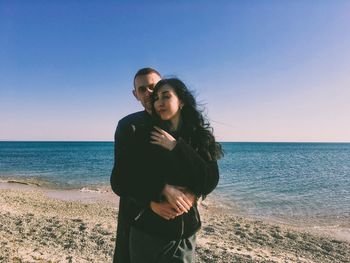 Lovers standing at beach against sky