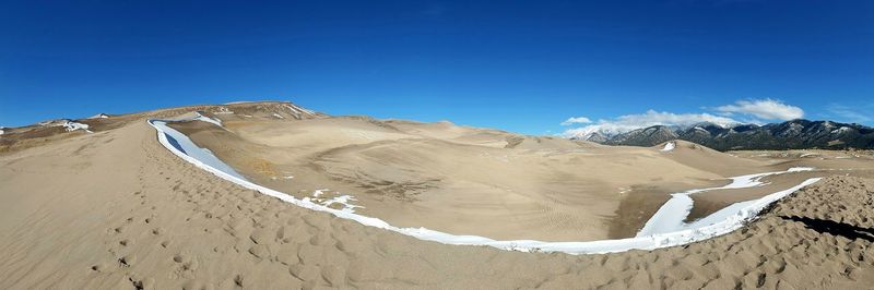 Sand dunes in desert against clear blue sky