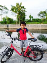 Full length portrait of boy with bicycle in water