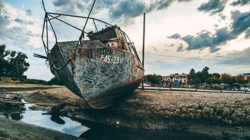 Abandoned boat on beach against sky