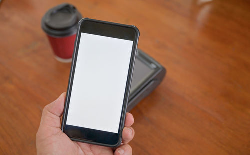 Midsection of person holding smart phone on table