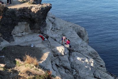 High angle view of people on rock by sea