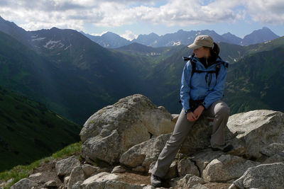 Man sitting on rock against mountains