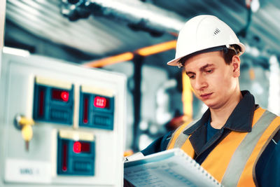 Industrial engineer in helmet inspects or adjusts equipment at gas processing plant or plant