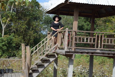 Portrait of young woman standing on steps against trees