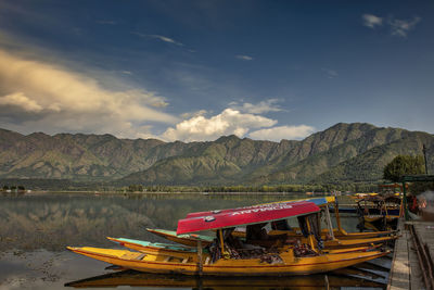 Fishing boats moored in lake against sky