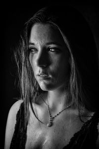 Close-up of woman crying against black background