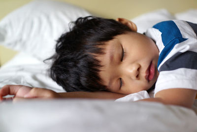 Close-up of baby sleeping on bed at home