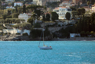 Sailboats in sea by buildings